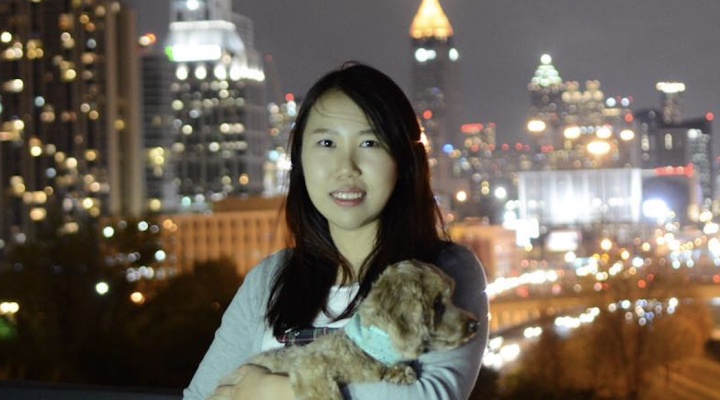 ECE Ph.D. student Danna Ma stands in front of a city skyline at night, holding her cat in her arms